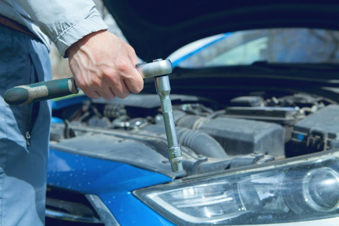Mechanic using a wrench on a car engine.